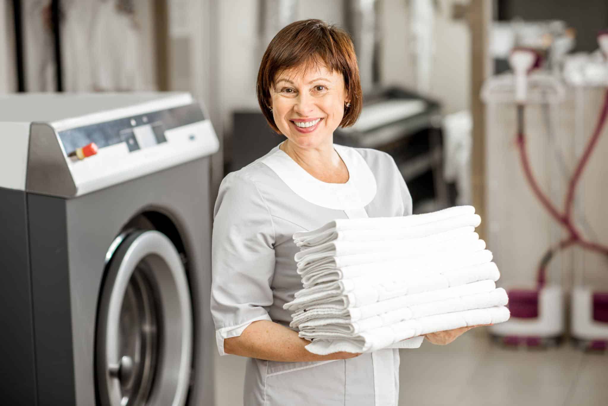 Professional laundry attendant holding neatly folded towels